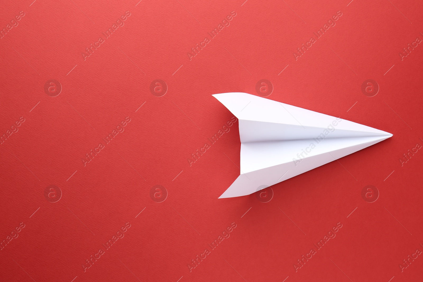 Photo of One handmade paper plane on red background, top view. Space for text