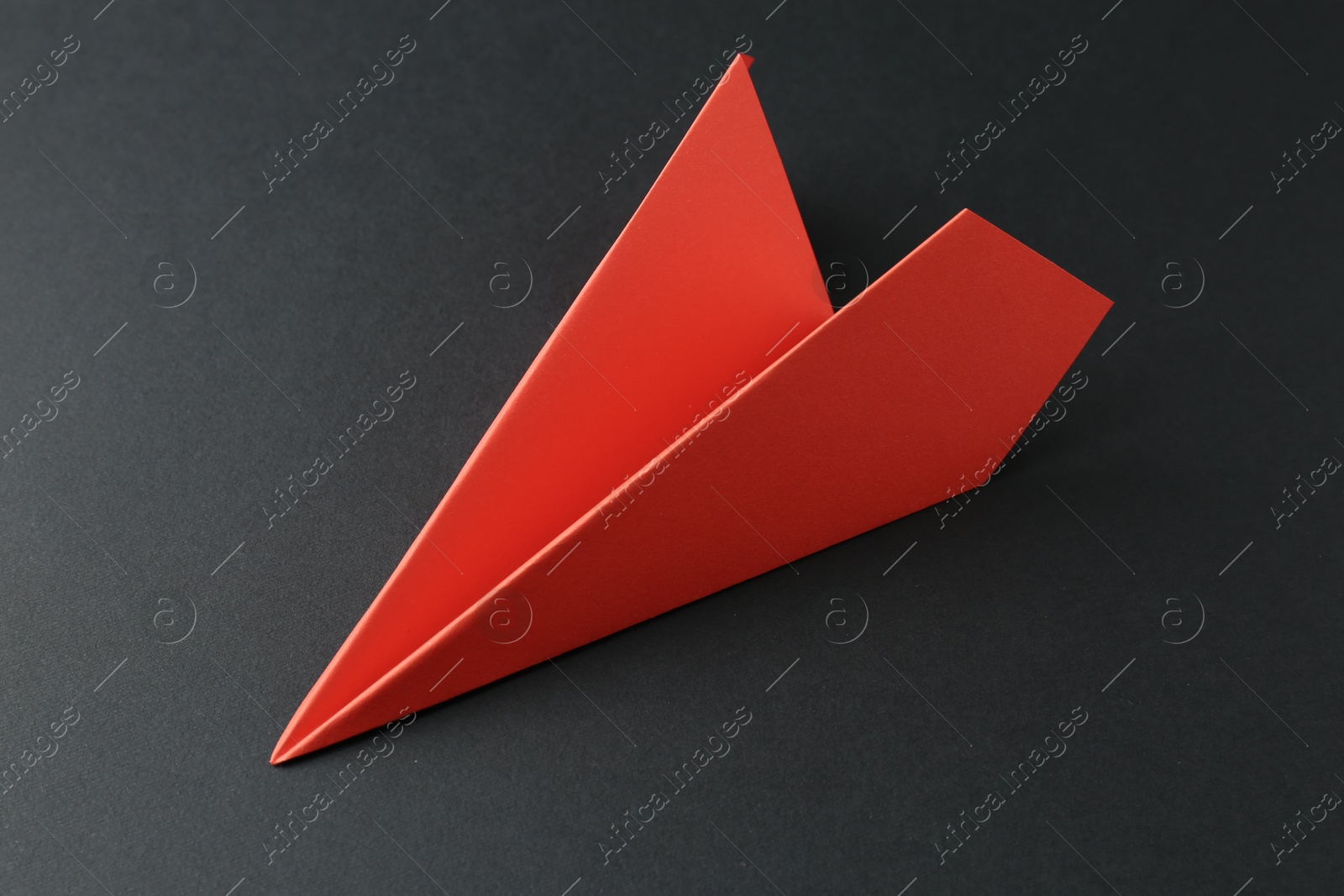 Photo of One handmade orange paper plane on grey background