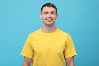 Smiling man with dental braces on light blue background