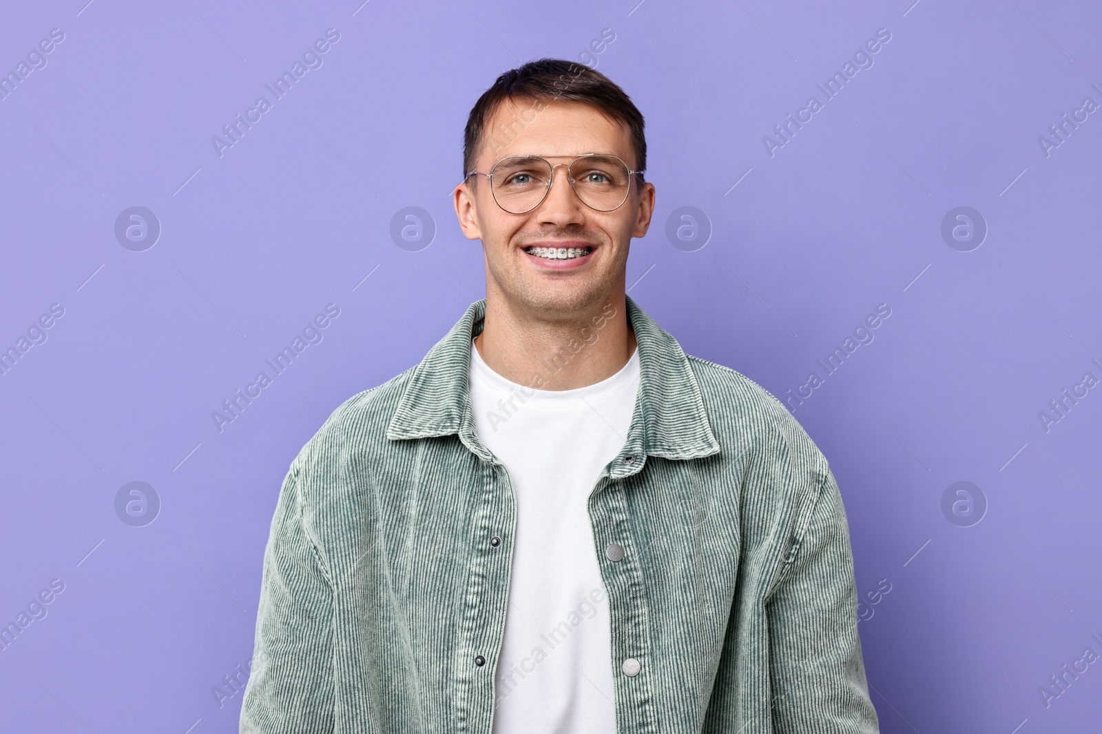 Photo of Smiling man with dental braces on violet background