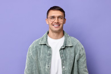 Smiling man with dental braces on violet background