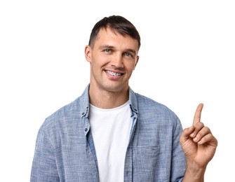 Smiling man with dental braces pointing at something on white background