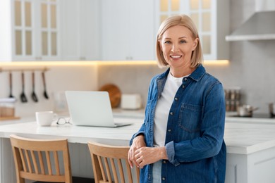 Happy middle aged woman in kitchen, space for text