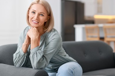 Happy middle aged woman on sofa indoors, space for text