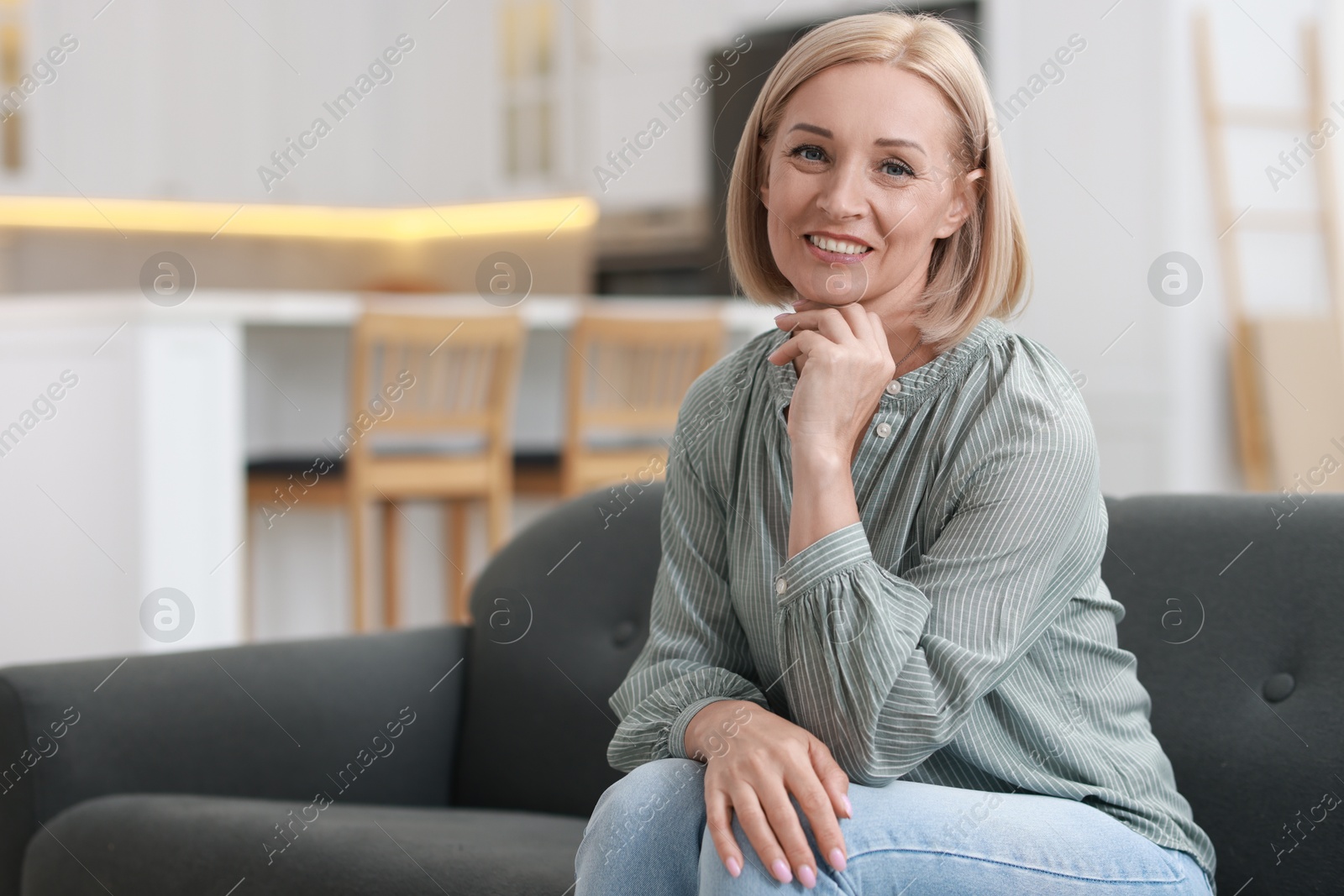 Photo of Happy middle aged woman on sofa indoors, space for text