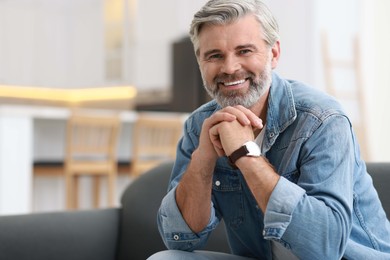 Happy middle aged man on sofa indoors, space for text