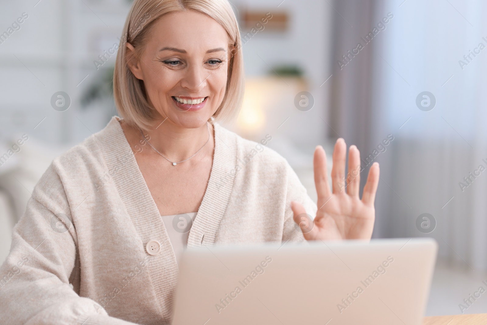 Photo of Happy middle aged woman having video chat via laptop indoors