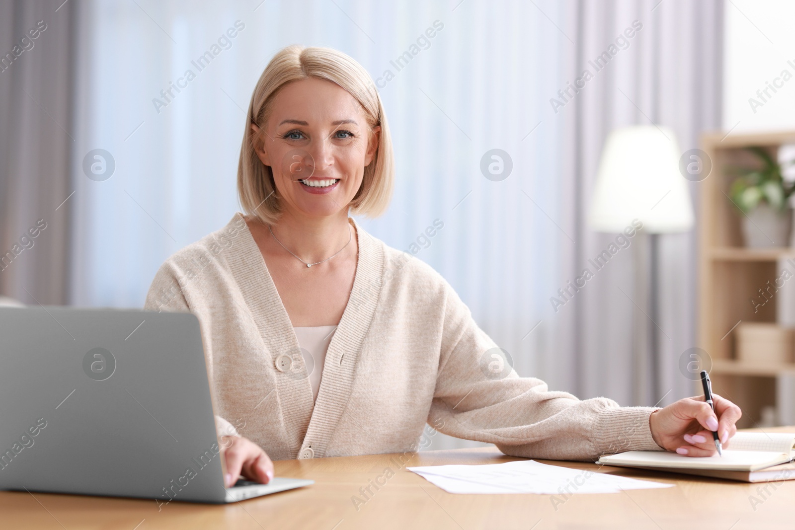 Photo of Happy middle aged woman working at table indoors