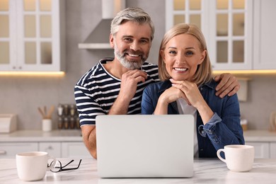 Happy middle aged couple at white marble table in kitchen