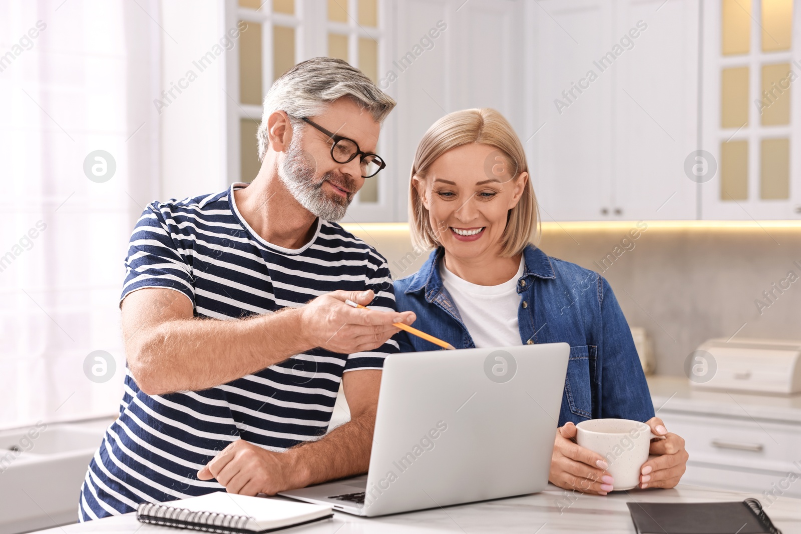 Photo of Middle aged couple working at white marble table in kitchen