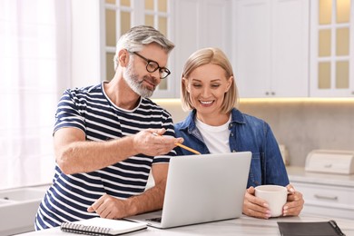 Middle aged couple working at white marble table in kitchen