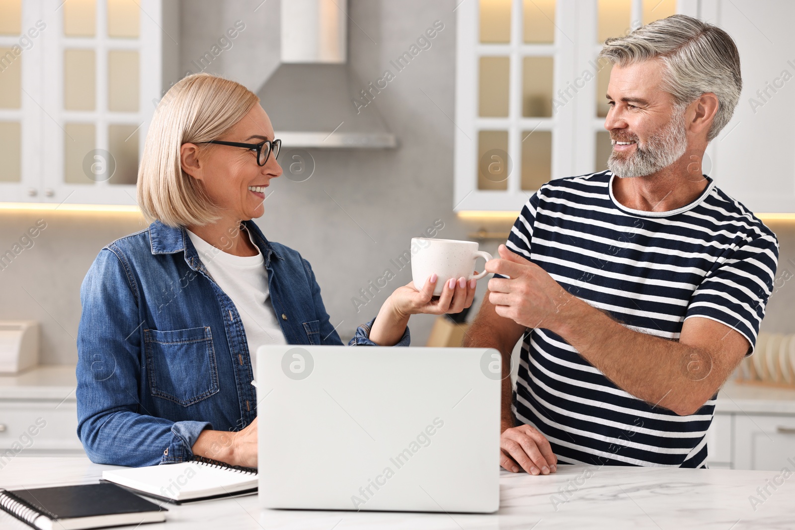 Photo of Happy middle aged couple spending time together in kitchen