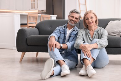 Portrait of happy middle aged couple on floor at home