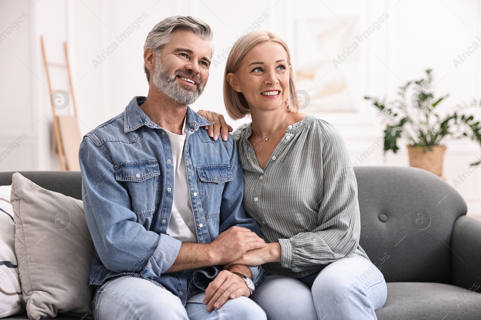 Photo of Happy middle aged couple on sofa at home