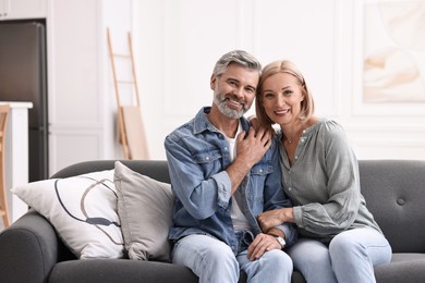 Portrait of happy middle aged couple on sofa at home