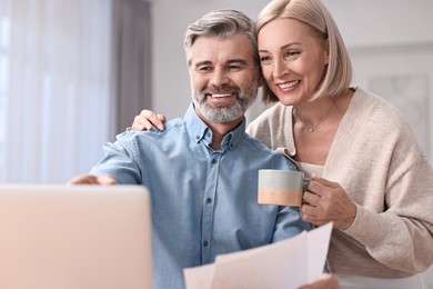 Photo of Happy middle aged couple using laptop indoors