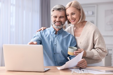 Photo of Happy middle aged couple working at table indoors