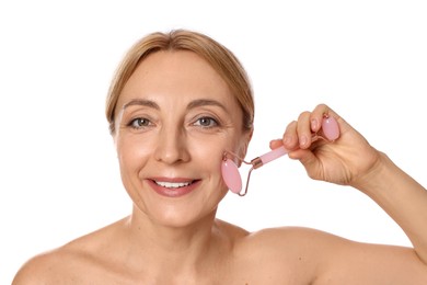 Smiling woman doing facial self massage with roller on white background