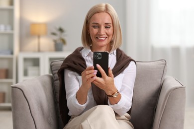 Smiling middle aged woman using smartphone at home