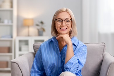 Photo of Portrait of smiling middle aged woman sitting on armchair at home