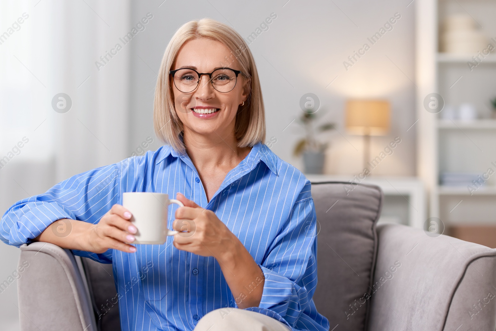 Photo of Smiling middle aged woman with cup of hot drink at home