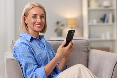 Smiling middle aged woman using smartphone at home