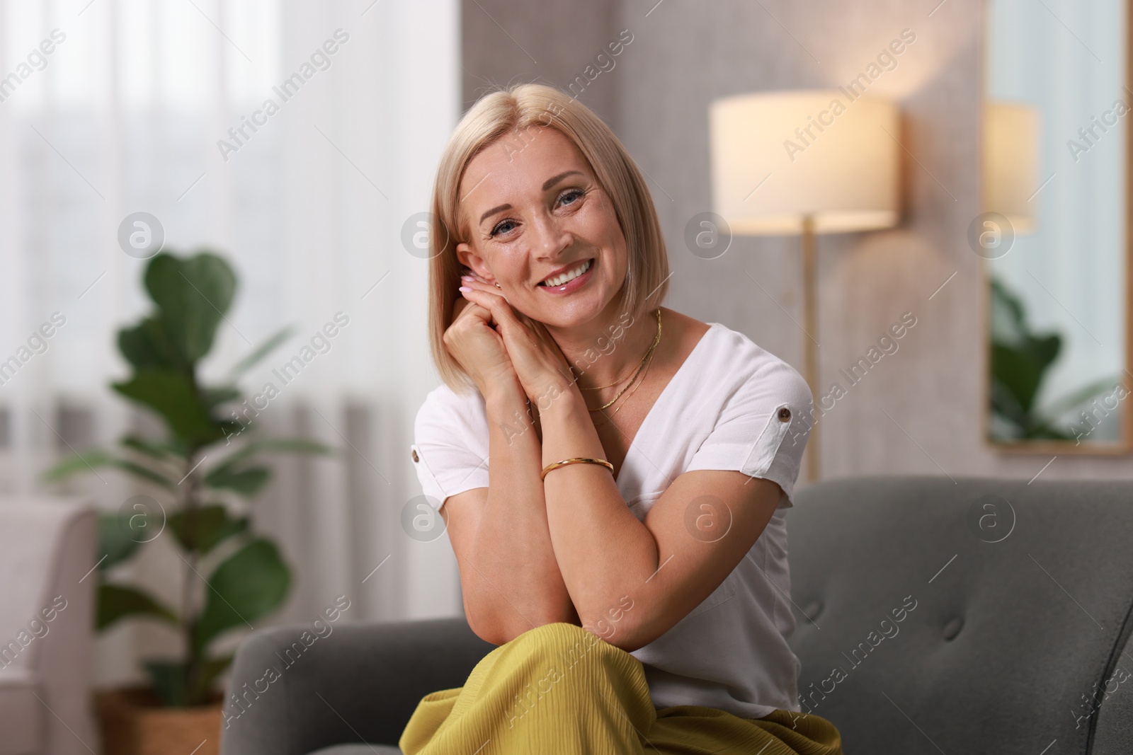 Photo of Portrait of smiling middle aged woman on sofa at home