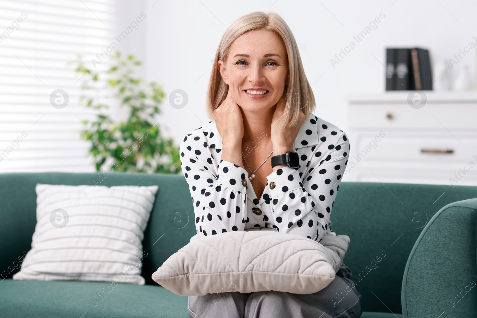 Photo of Portrait of smiling middle aged woman on sofa at home