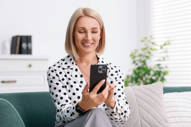 Portrait of smiling middle aged woman using smartphone at home