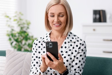 Portrait of smiling middle aged woman using smartphone at home