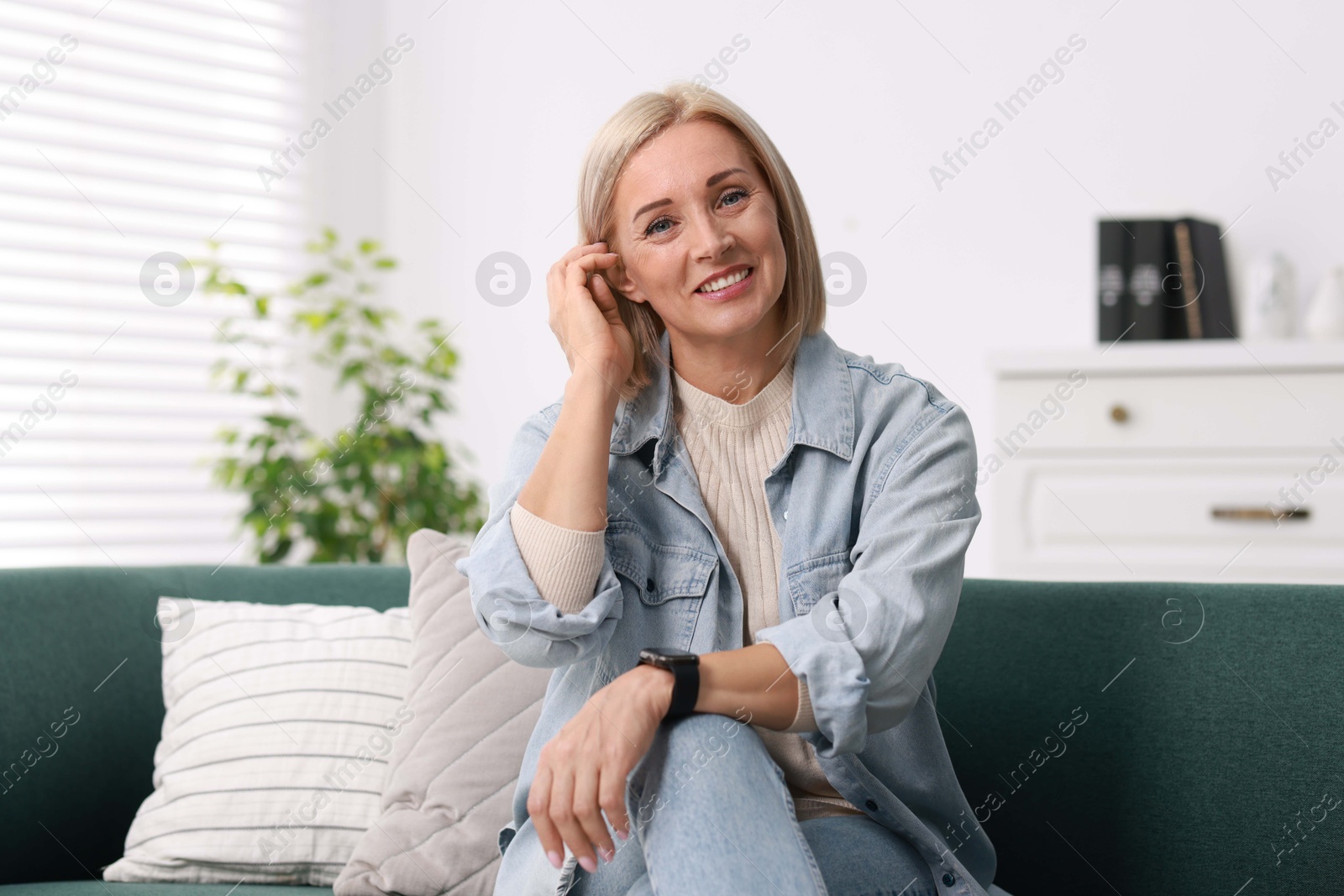 Photo of Portrait of smiling middle aged woman on sofa at home