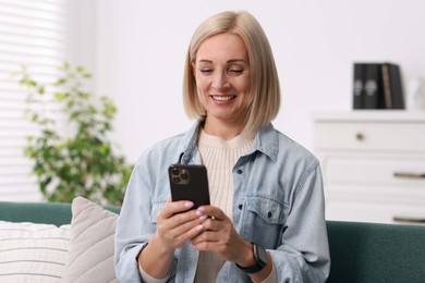 Portrait of smiling middle aged woman using smartphone at home