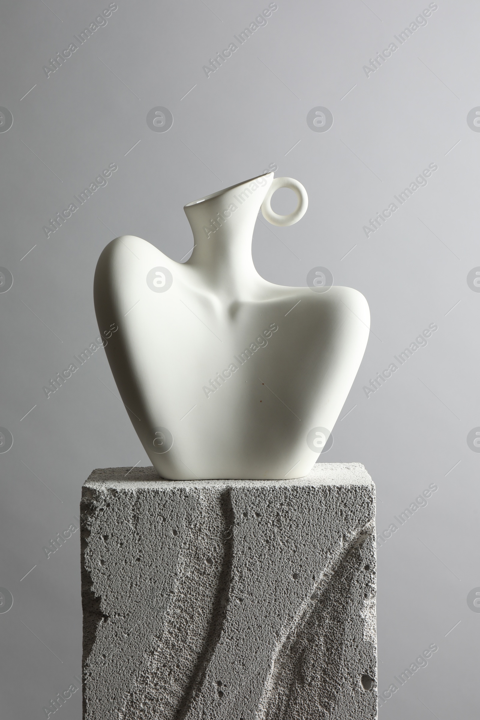 Photo of Stylish vase on concrete block against light grey background