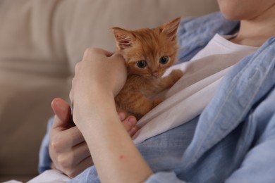 Teenage boy with his cute ginger kitten indoors, closeup