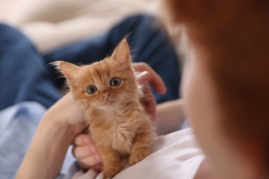 Photo of Teenage boy with his cute ginger kitten indoors, closeup