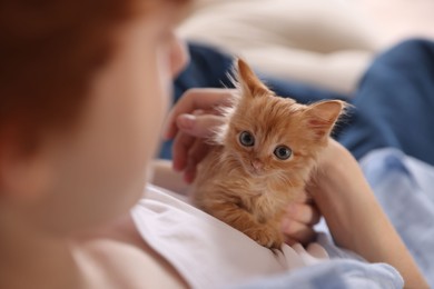 Teenage boy with his cute ginger kitten indoors, closeup