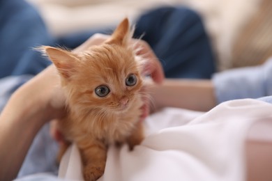 Photo of Teenage boy with his cute ginger kitten indoors, closeup