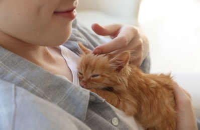 Teenage boy with his cute ginger kitten indoors, closeup