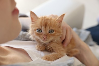 Photo of Teenage boy with his cute ginger kitten indoors, closeup