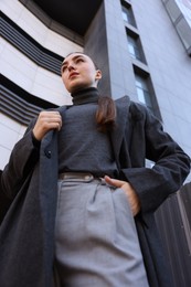 Photo of Beautiful young woman with black coat posing outdoors, low angle view