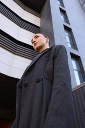 Beautiful young woman with black coat posing outdoors, low angle view