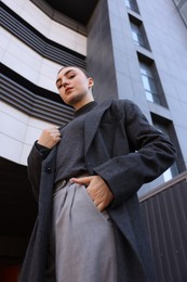 Beautiful young woman with black coat posing outdoors, low angle view