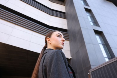 Beautiful young woman with black coat posing outdoors, low angle view