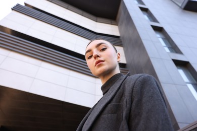 Beautiful young woman with black coat posing outdoors, low angle view