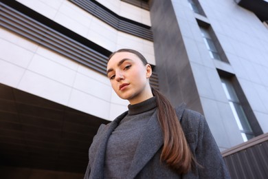 Beautiful young woman with black coat posing outdoors, low angle view