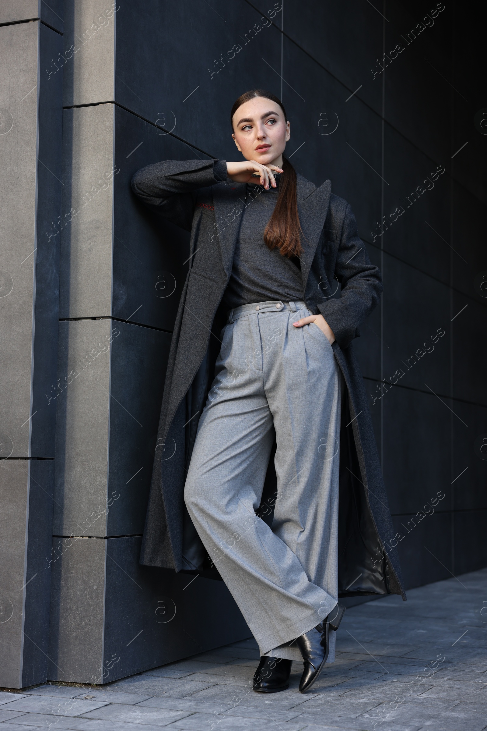 Photo of Beautiful young woman with black coat posing outdoors