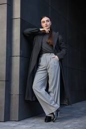 Photo of Beautiful young woman with black coat posing outdoors