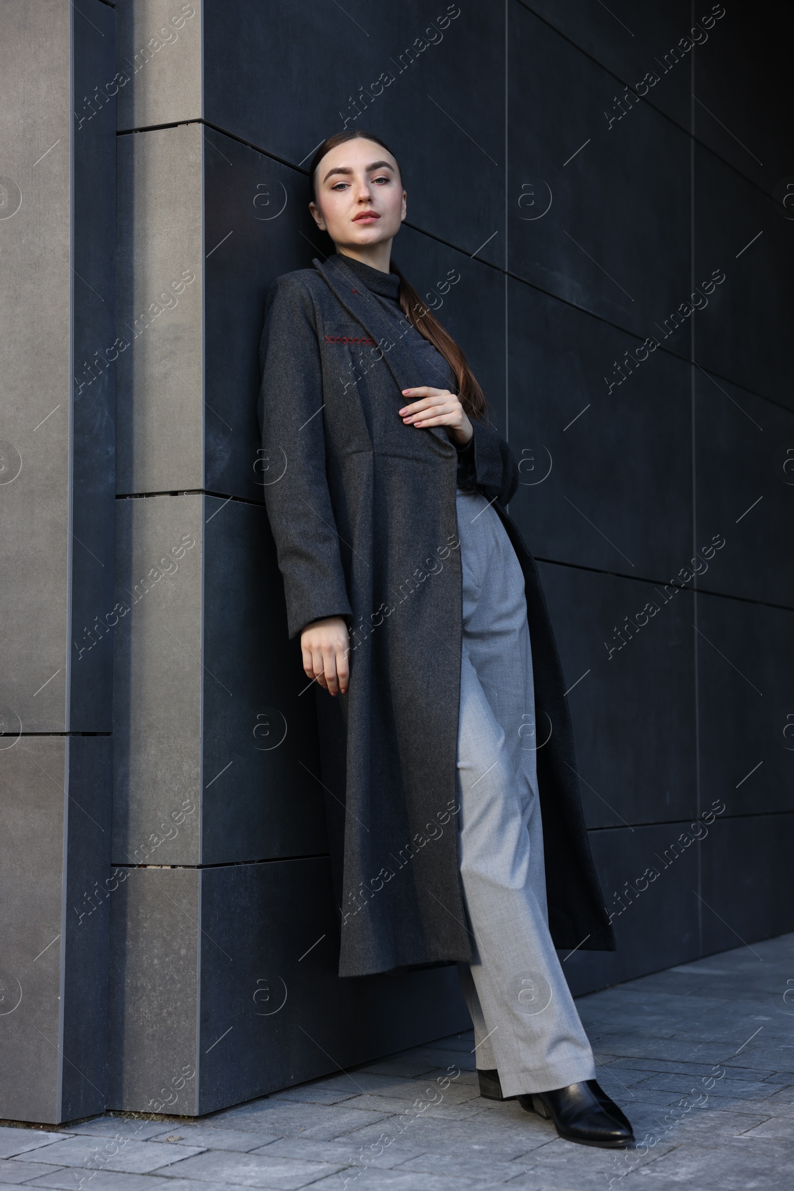 Photo of Beautiful young woman with black coat posing outdoors