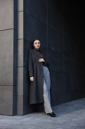 Photo of Beautiful young woman with black coat posing outdoors