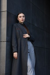 Photo of Beautiful young woman with black coat posing outdoors